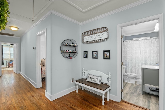 corridor with crown molding, attic access, wood finished floors, and baseboards