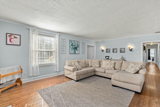 living room featuring visible vents, ornamental molding, hardwood / wood-style flooring, a textured ceiling, and baseboards