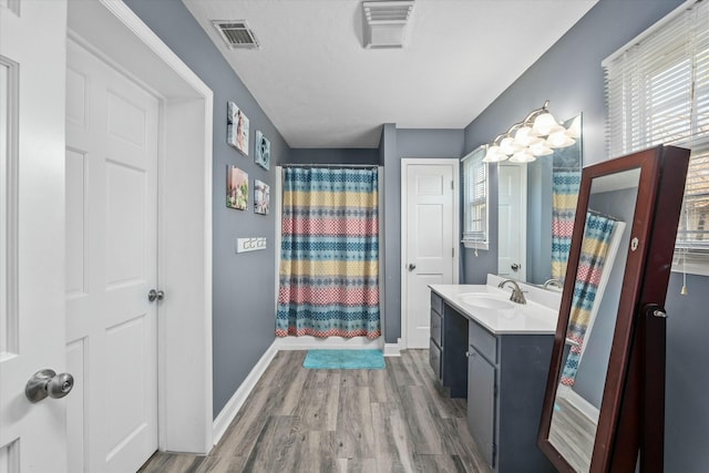 bathroom with vanity, a shower with curtain, wood finished floors, visible vents, and baseboards