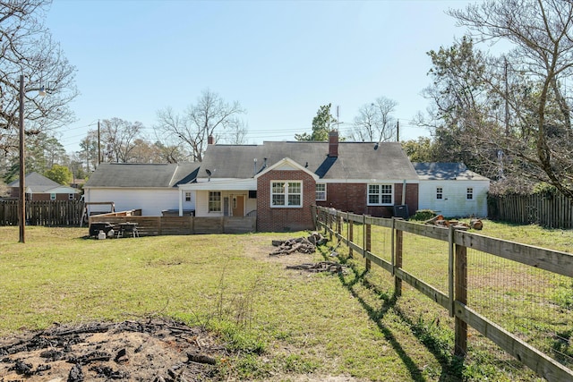 rear view of house with a fenced backyard, brick siding, and a yard