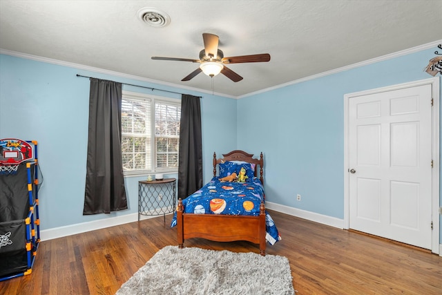 bedroom featuring wood finished floors, visible vents, and ornamental molding