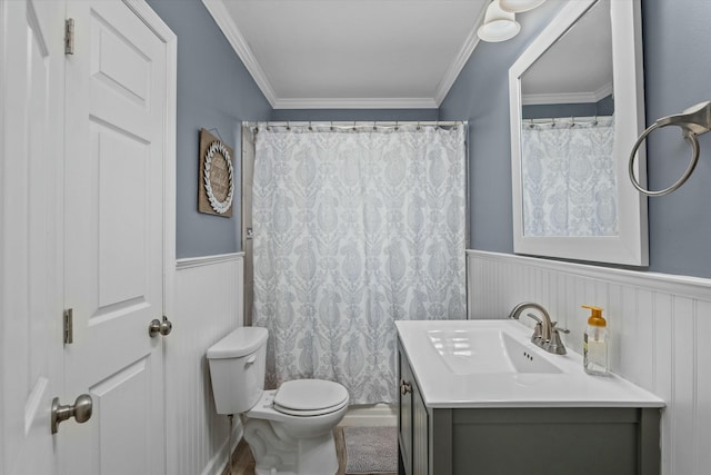 full bathroom with vanity, ornamental molding, toilet, and wainscoting