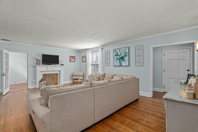 living room featuring a fireplace with flush hearth, dark wood-style floors, visible vents, and baseboards