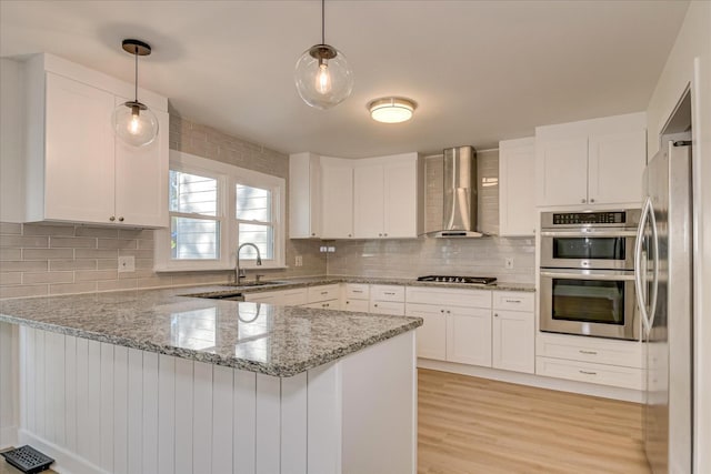 3408 Wheeler Rd, Augusta, GA 30909 - kitchen featuring wall chimney exhaust hood, a peninsula, a sink, stainless steel appliances, and white cabinets
