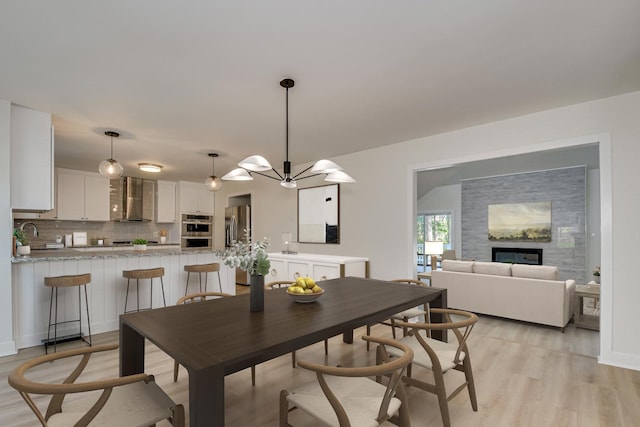 3408 Wheeler Rd, Augusta, GA 30909 - dining space with light wood-style flooring, a chandelier, and a glass covered fireplace