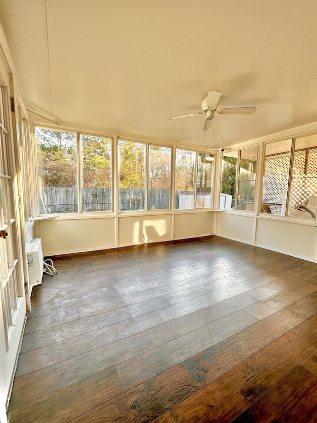 unfurnished sunroom featuring a wall mounted air conditioner and ceiling fan