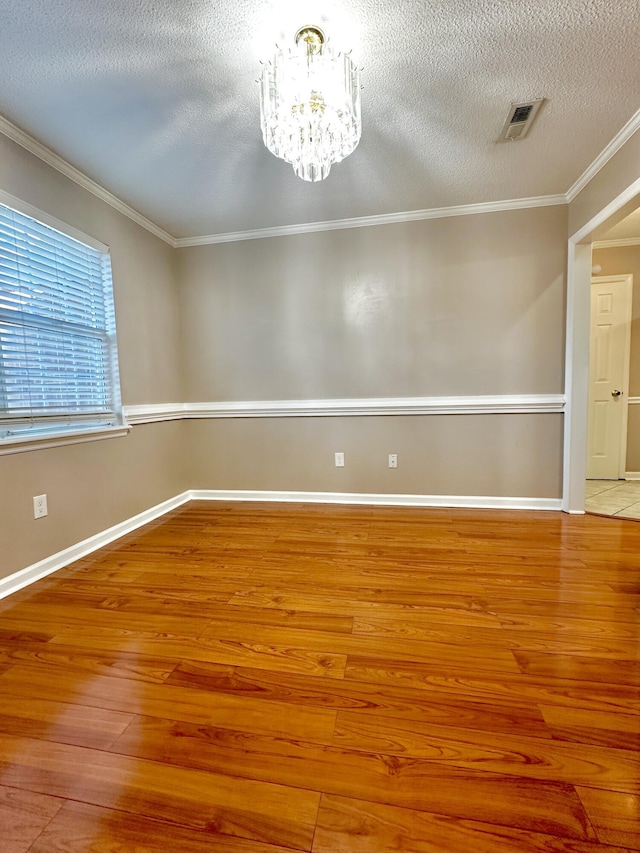 unfurnished room featuring crown molding, light hardwood / wood-style flooring, a chandelier, and a textured ceiling