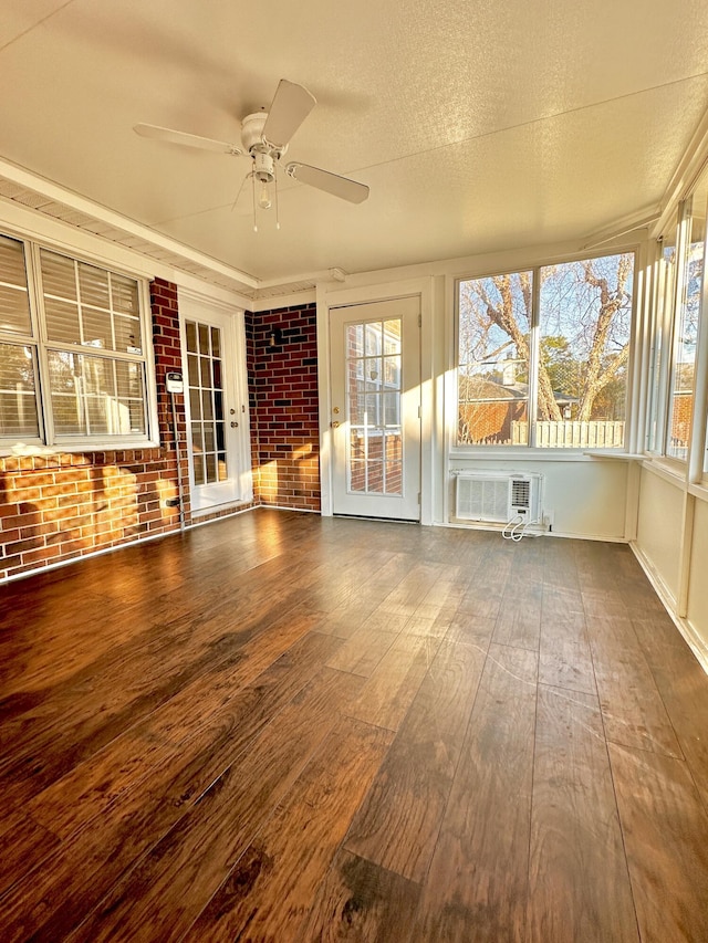 unfurnished sunroom featuring an AC wall unit and ceiling fan