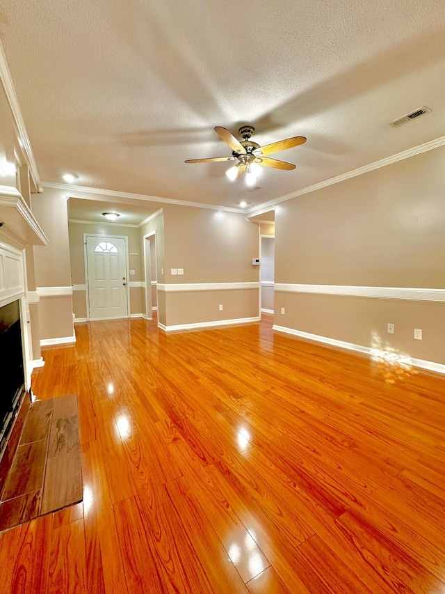 unfurnished living room with ceiling fan, crown molding, and a textured ceiling