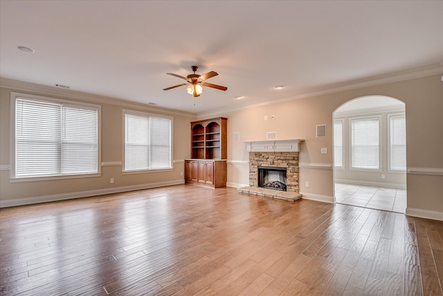 514 Hardwick Ct, Evans, GA 30809 - unfurnished living room with a ceiling fan, crown molding, light wood-style floors, plenty of natural light, and a stone fireplace