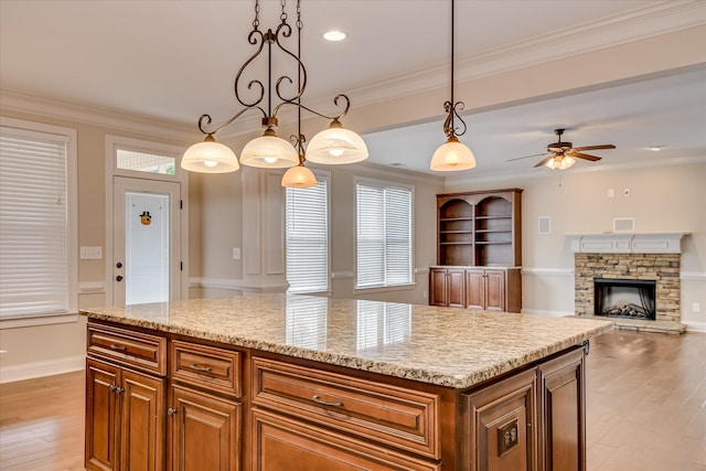 514 Hardwick Ct, Evans, GA 30809 - kitchen featuring light wood finished floors, ceiling fan, a stone fireplace, light stone counters, and ornamental molding