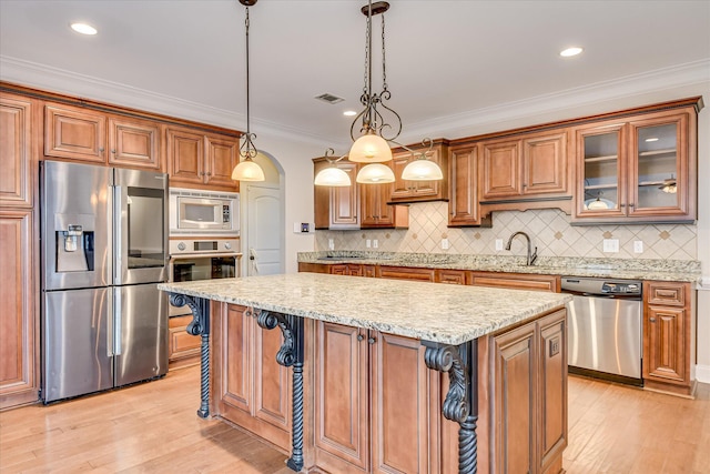 514 Hardwick Ct, Evans, GA 30809 - kitchen featuring stainless steel appliances, light wood finished floors, a center island, light stone countertops, and brown cabinets