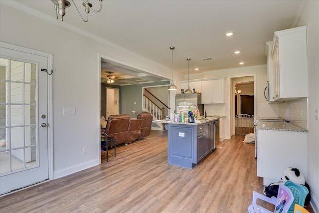 3015 Bannack Ln, Harlem, GA 30814 - kitchen with white cabinetry, open floor plan, a center island with sink, decorative backsplash, and light wood-style flooring