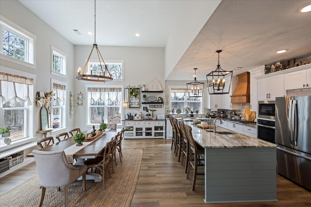 kitchen featuring an inviting chandelier, custom exhaust hood, stainless steel appliances, and a sink