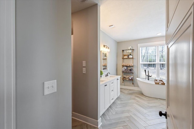 full bathroom featuring a sink, visible vents, baseboards, a freestanding bath, and double vanity