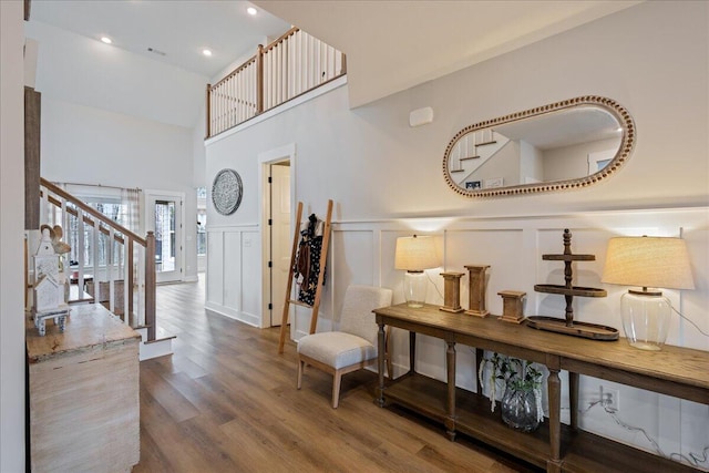 entrance foyer with wainscoting, stairway, wood finished floors, a decorative wall, and recessed lighting