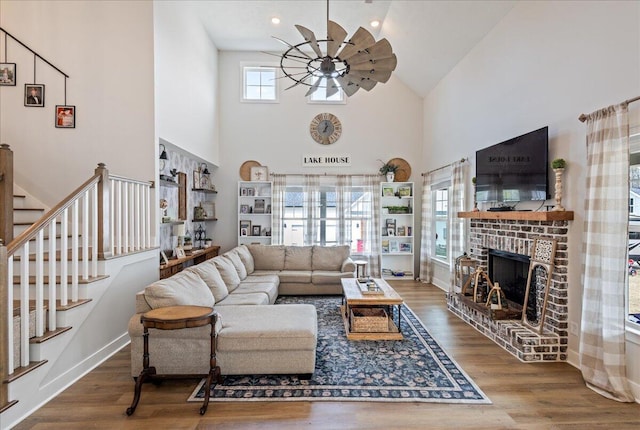 living area featuring a ceiling fan, stairs, a fireplace, and wood finished floors