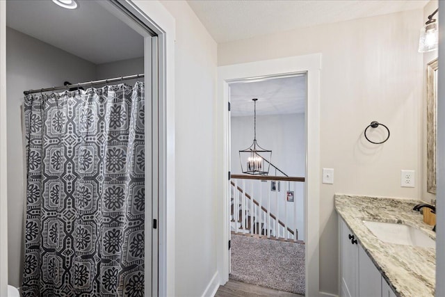 full bathroom with a chandelier, a shower with curtain, vanity, and wood finished floors