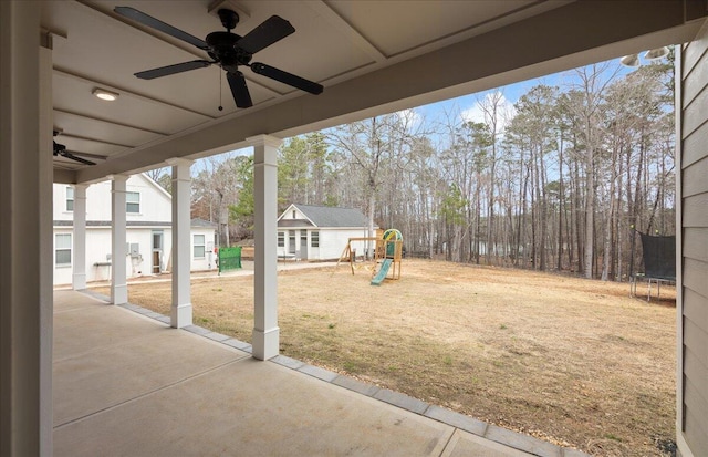 view of yard featuring ceiling fan, a trampoline, a playground, and a patio