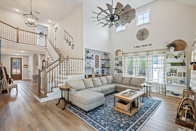 living area with baseboards, stairway, wood finished floors, and ceiling fan with notable chandelier