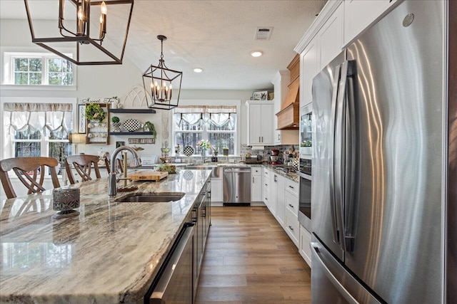 kitchen with a notable chandelier, stainless steel appliances, visible vents, dark wood-type flooring, and a sink