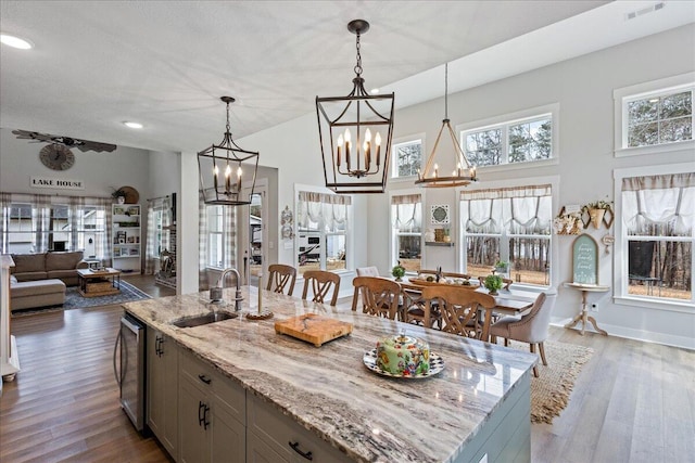 kitchen with dark wood-style flooring, a sink, visible vents, and light stone countertops