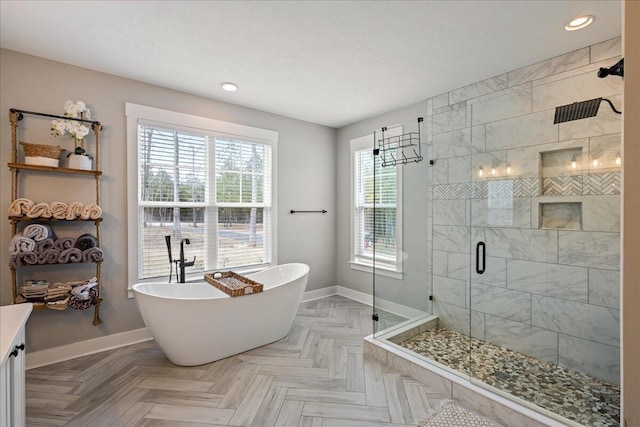 bathroom with a freestanding bath, a stall shower, recessed lighting, and baseboards