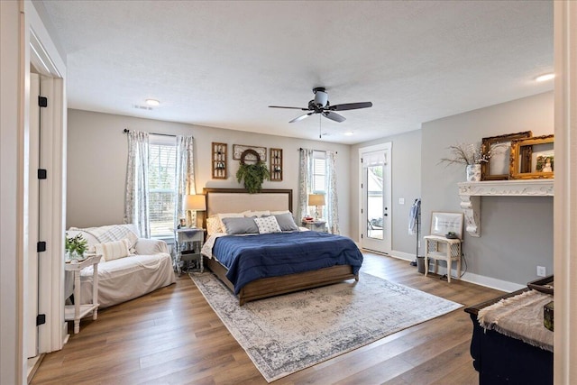 bedroom featuring visible vents, baseboards, ceiling fan, wood finished floors, and access to exterior