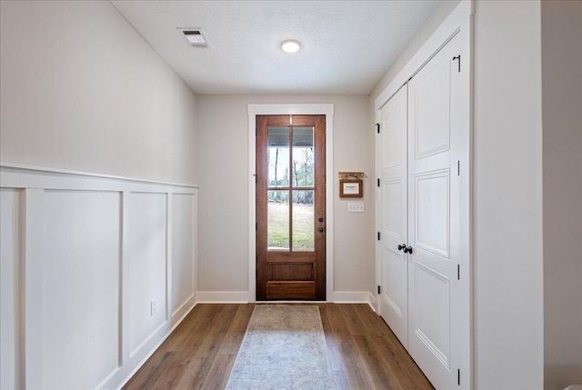 entrance foyer with wainscoting, wood finished floors, and visible vents