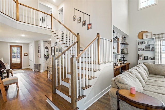 staircase with a towering ceiling, baseboards, and wood finished floors