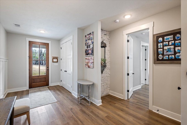 foyer entrance featuring baseboards, visible vents, and wood finished floors