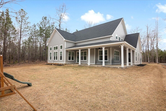 view of side of property with a yard, a playground, ceiling fan, and roof with shingles