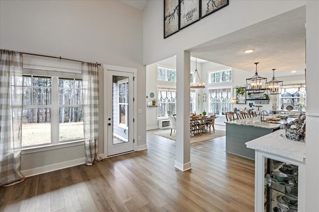 foyer entrance featuring a chandelier, light wood-type flooring, a towering ceiling, and baseboards