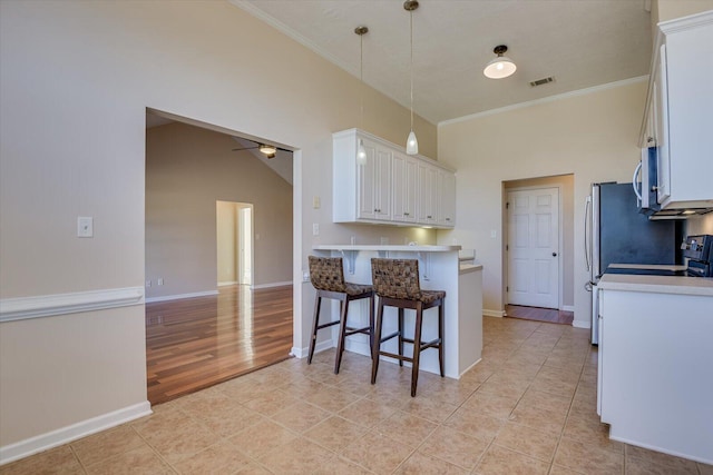 kitchen featuring white cabinets, hanging light fixtures, crown molding, ceiling fan, and a breakfast bar area