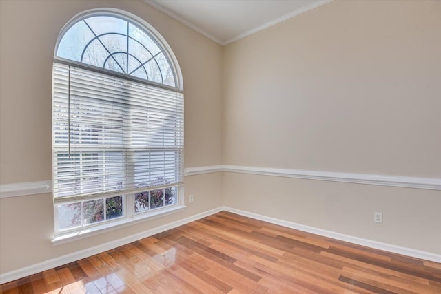 spare room with wood-type flooring, a wealth of natural light, and ornamental molding