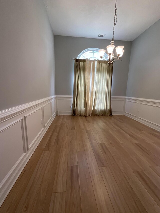1129 Waltons Trl, Hephzibah, GA 30815 - unfurnished room featuring a chandelier, a decorative wall, wood finished floors, and a wainscoted wall