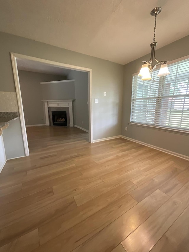 1129 Waltons Trl, Hephzibah, GA 30815 - unfurnished dining area featuring a chandelier, light wood-style flooring, a fireplace, and baseboards