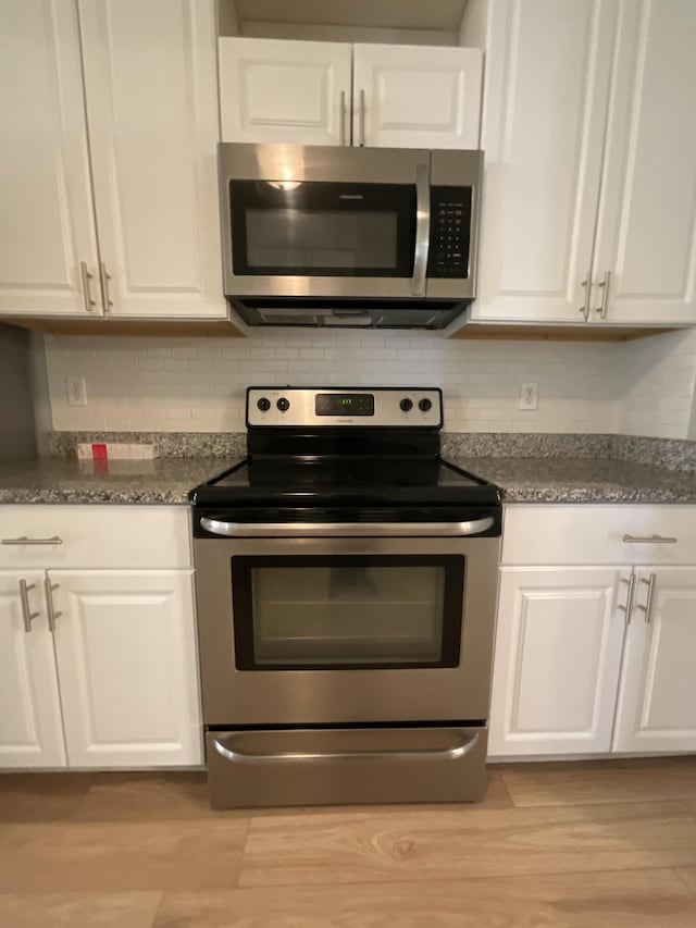 1129 Waltons Trl, Hephzibah, GA 30815 - kitchen with appliances with stainless steel finishes, white cabinetry, light wood-style floors, and backsplash