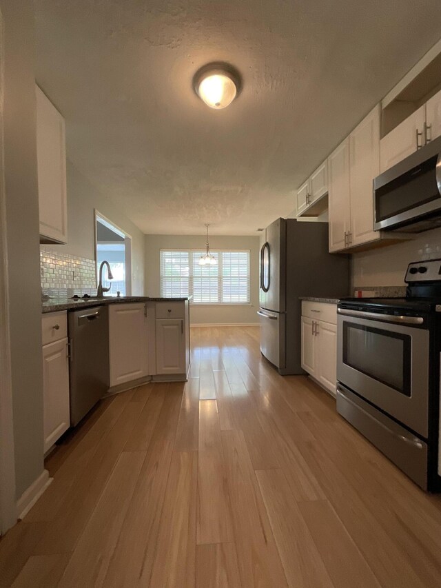 1129 Waltons Trl, Hephzibah, GA 30815 - kitchen featuring appliances with stainless steel finishes, white cabinets, a peninsula, and light wood-type flooring