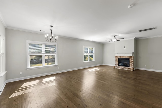 unfurnished living room with crown molding, dark hardwood / wood-style floors, ceiling fan with notable chandelier, and a brick fireplace