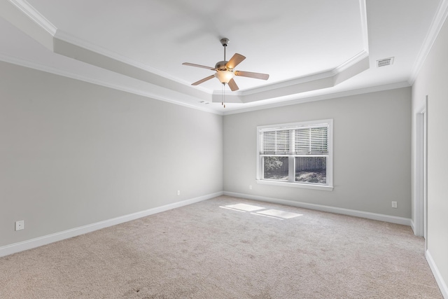 spare room featuring a tray ceiling, ceiling fan, ornamental molding, and light colored carpet