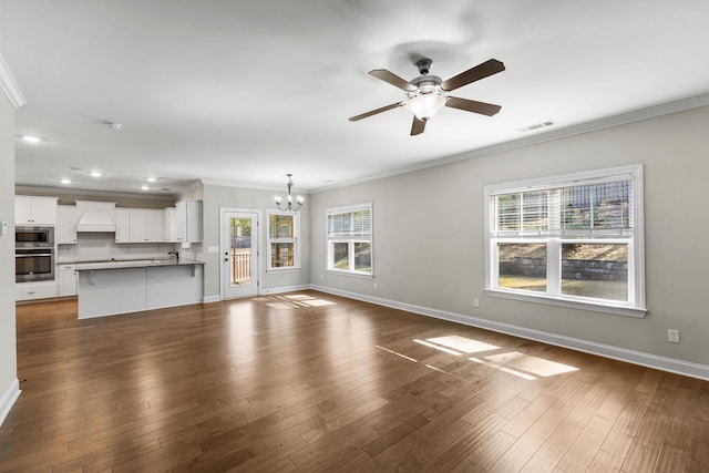 unfurnished living room with ceiling fan with notable chandelier, dark hardwood / wood-style floors, and crown molding