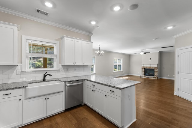 kitchen with sink, a brick fireplace, stainless steel dishwasher, white cabinets, and ceiling fan with notable chandelier