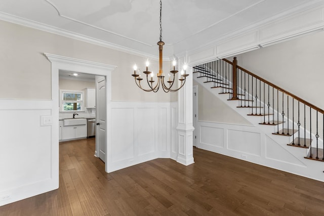 unfurnished dining area with dark hardwood / wood-style flooring, crown molding, sink, and a chandelier