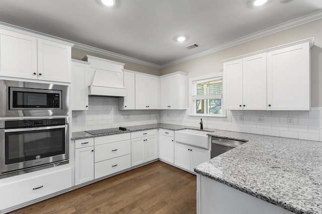 kitchen with light stone counters, ornamental molding, stainless steel appliances, sink, and white cabinets