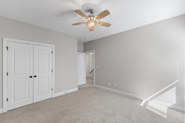 unfurnished bedroom with ceiling fan, light carpet, and a closet