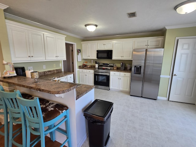 318 Elbrus Way, Grovetown, GA 30813 - kitchen featuring stainless steel appliances, dark countertops, ornamental molding, a peninsula, and white cabinetry