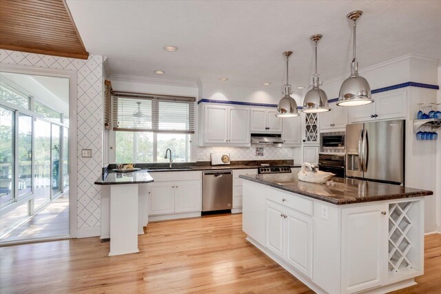 kitchen featuring white cabinets, decorative light fixtures, stainless steel appliances, and a kitchen island