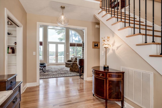 foyer with french doors and light hardwood / wood-style flooring