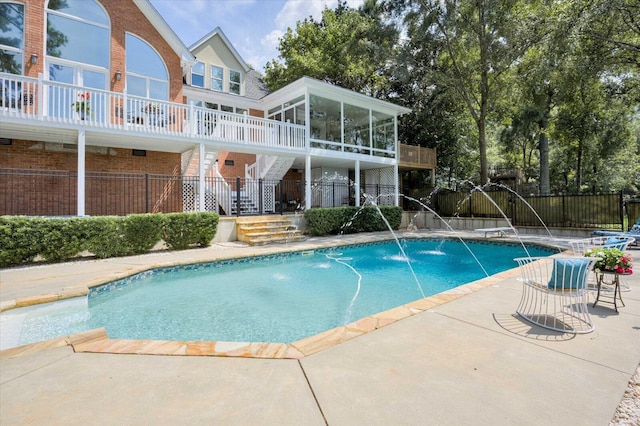 view of swimming pool with a sunroom, pool water feature, and a patio area